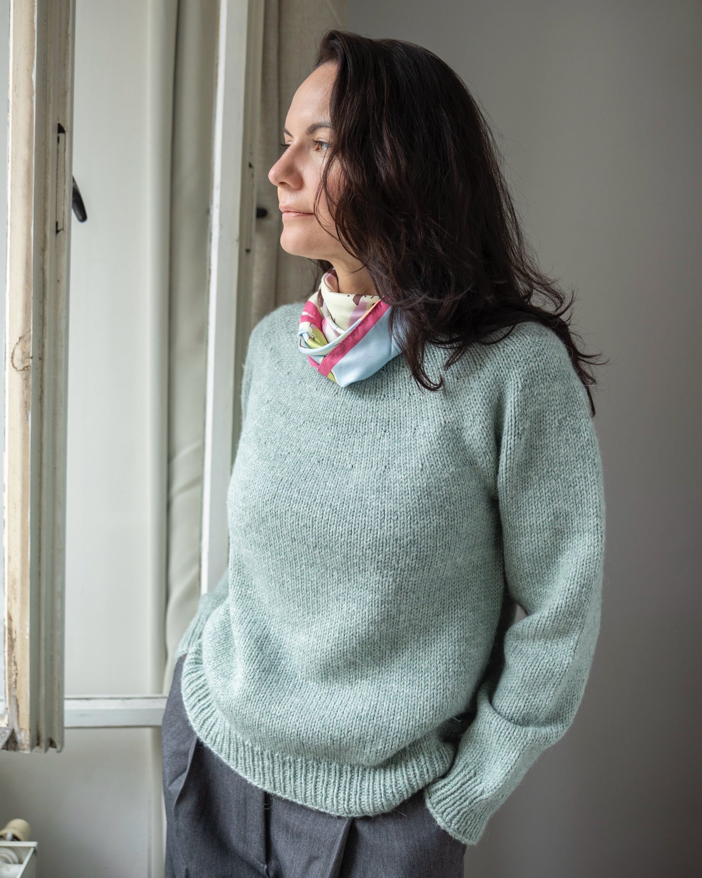 Woman wearing a light blue sweater standing indoors with a neutral background