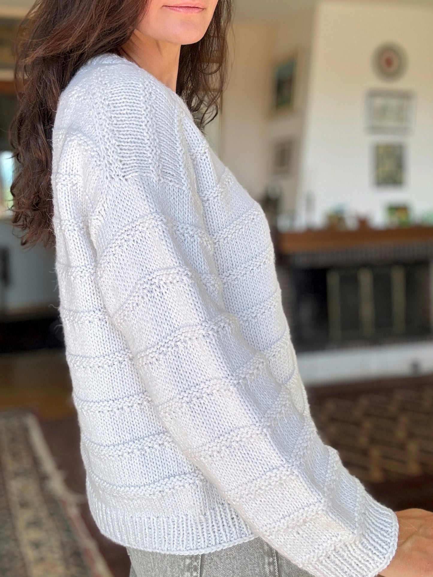 Close-up of Julia Piro modeling a cozy knit pullover with ribbed hem and patterned ridges in soft yarn.