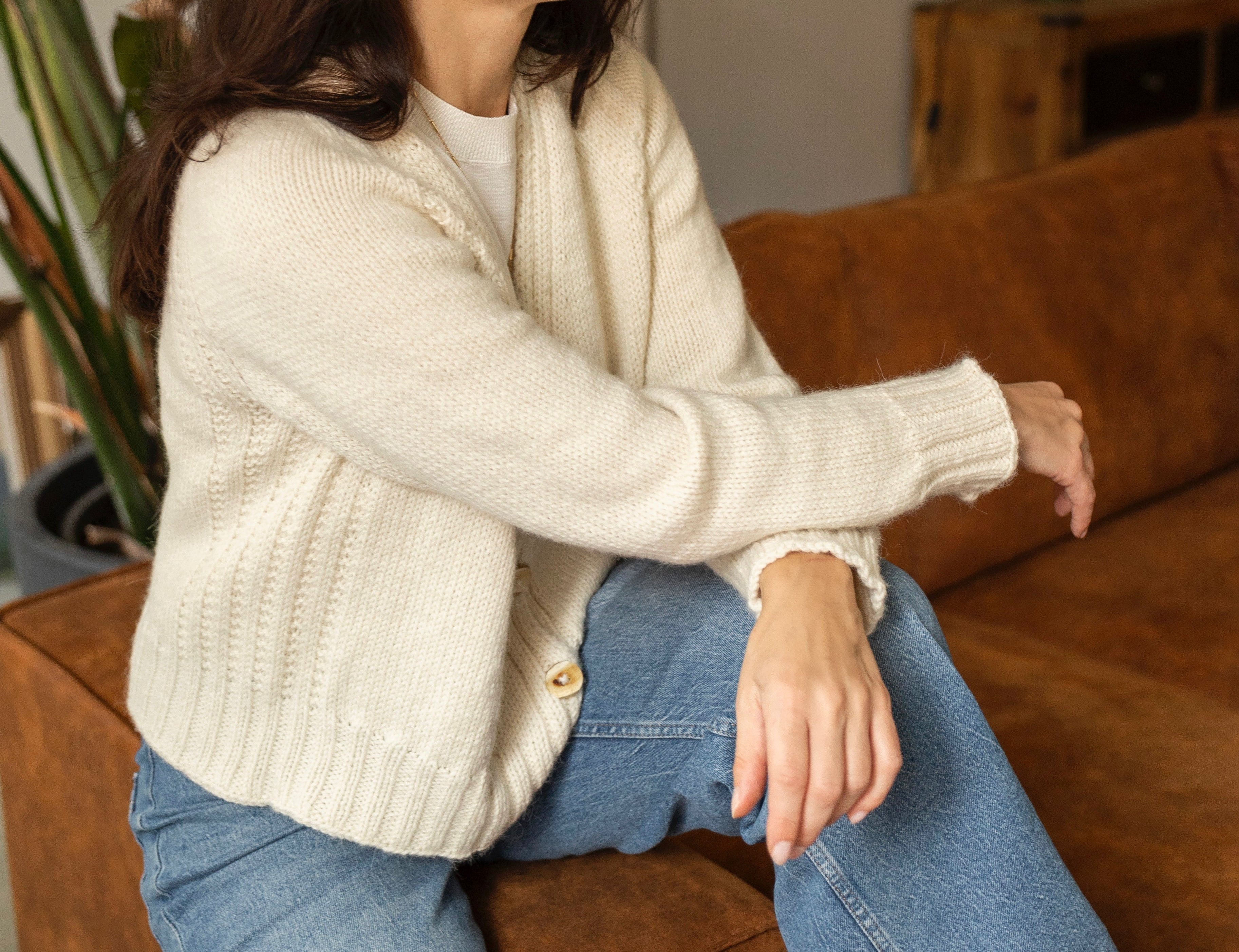 Woman in the Mellow Mood cardigan sitting on a brown couch 