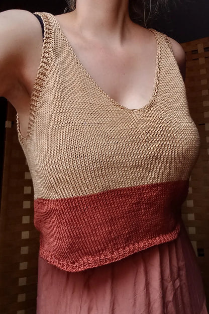 Person wearing a two-tone knitted tank top with beige and red colors.