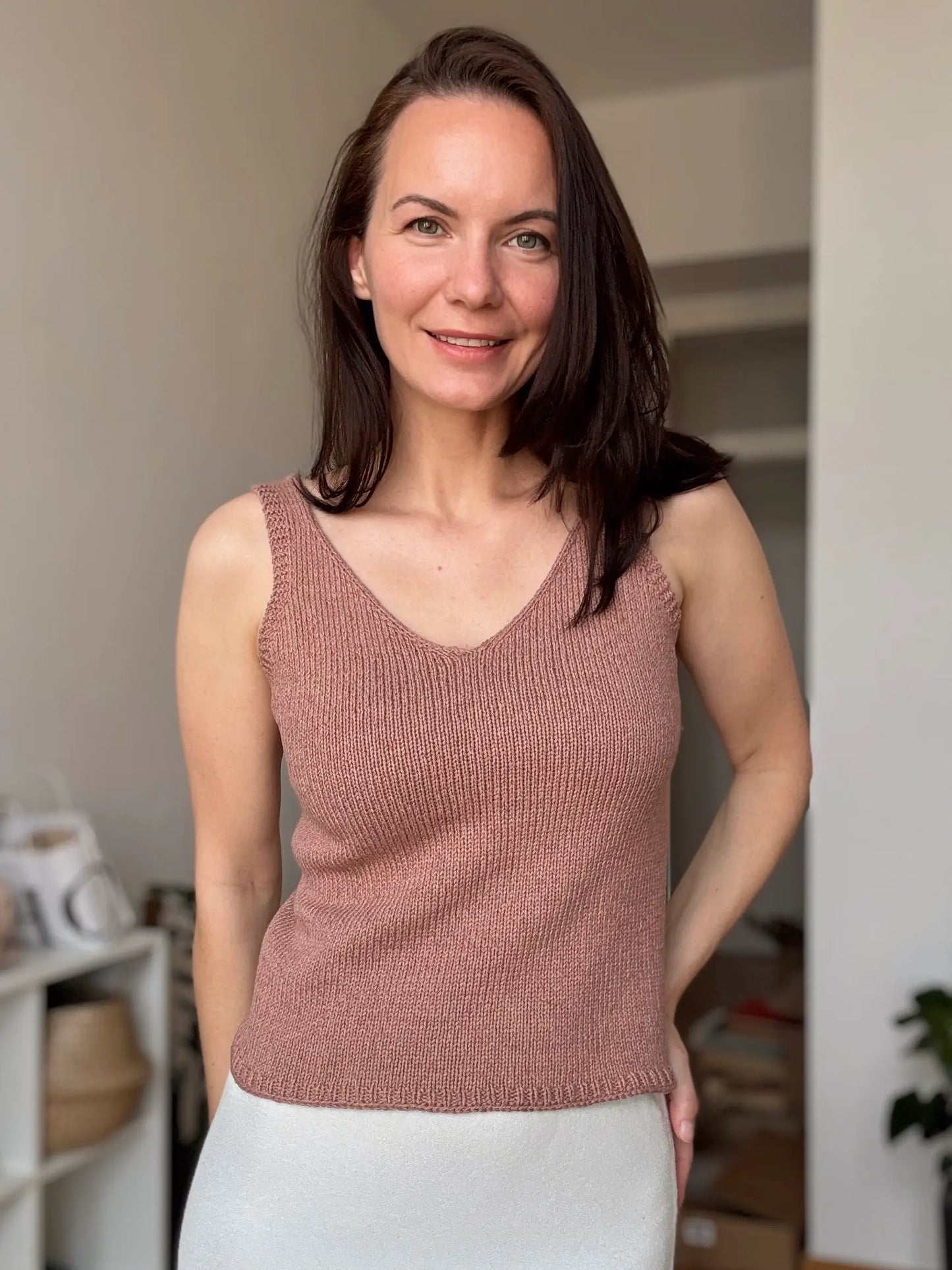 Woman wearing a pink knitted tank top in an indoor setting