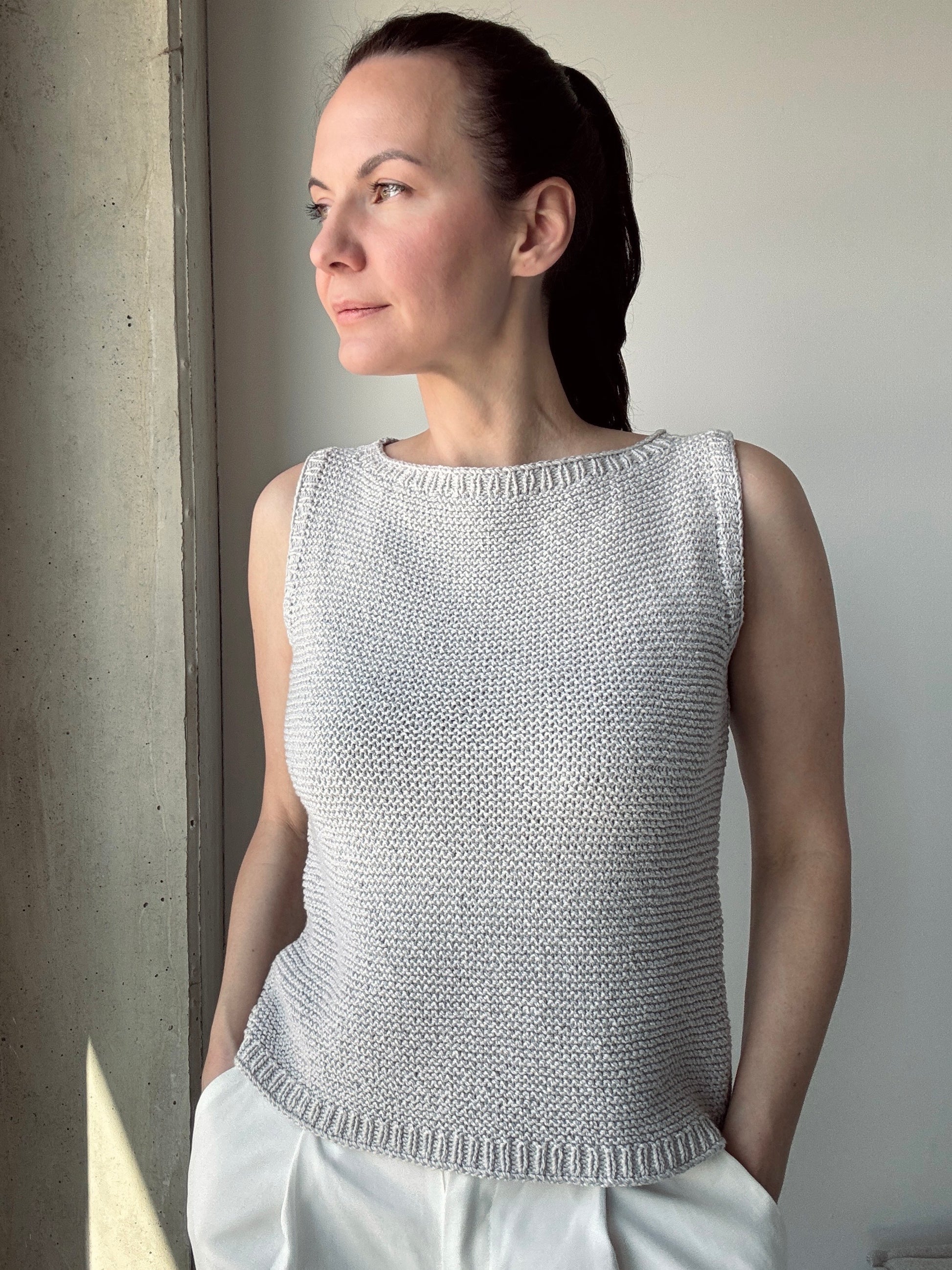 Front view of the Summer Soul Top in light grey, worn with white pants. Features a relaxed fit, sleeveless design, and textured garter stitch.