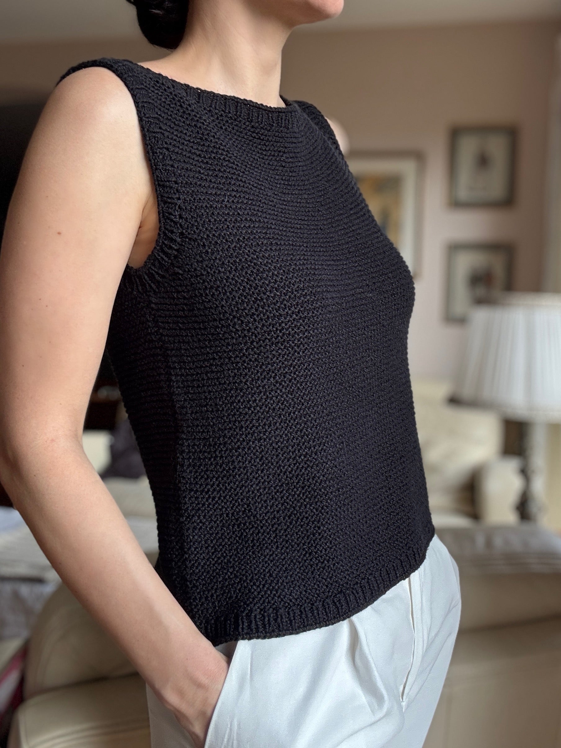 Person wearing a black sleeveless top in a casual setting.